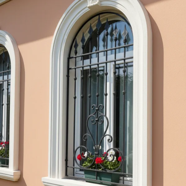Ornamental black wrought iron window security grille with spear tips and central heart-shaped scrollwork on an arched window.