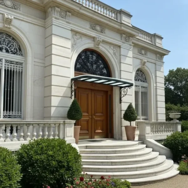 Luxury neo-classical building entrance with a grand staircase and a curved black wrought iron canopy with glass roofing, set against a limestone facade.